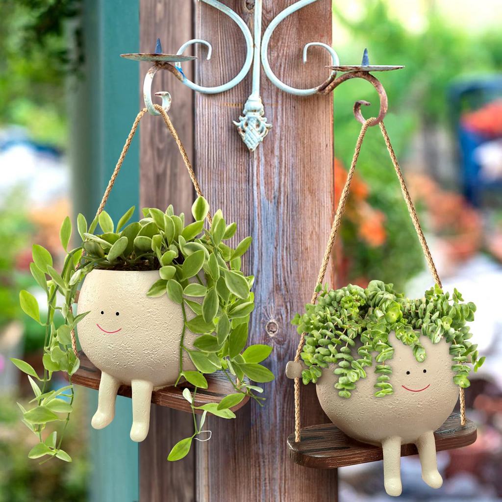 Two Miniko Swing Time planters with trailing plants hanging on a garden post
